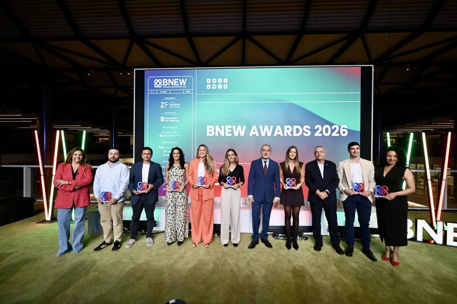 Foto de grup de les vuit startups guardonades als BNEW Awards 2026 amb els trofeus, al costat de les autoritats